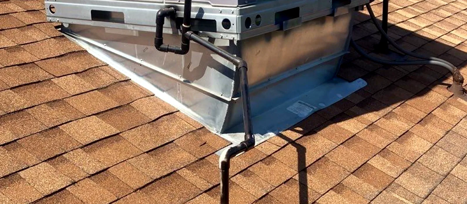 Rooftop air conditioning unit on a Fresno home with new metal flashing and matched composition shingles around a properly secured stand