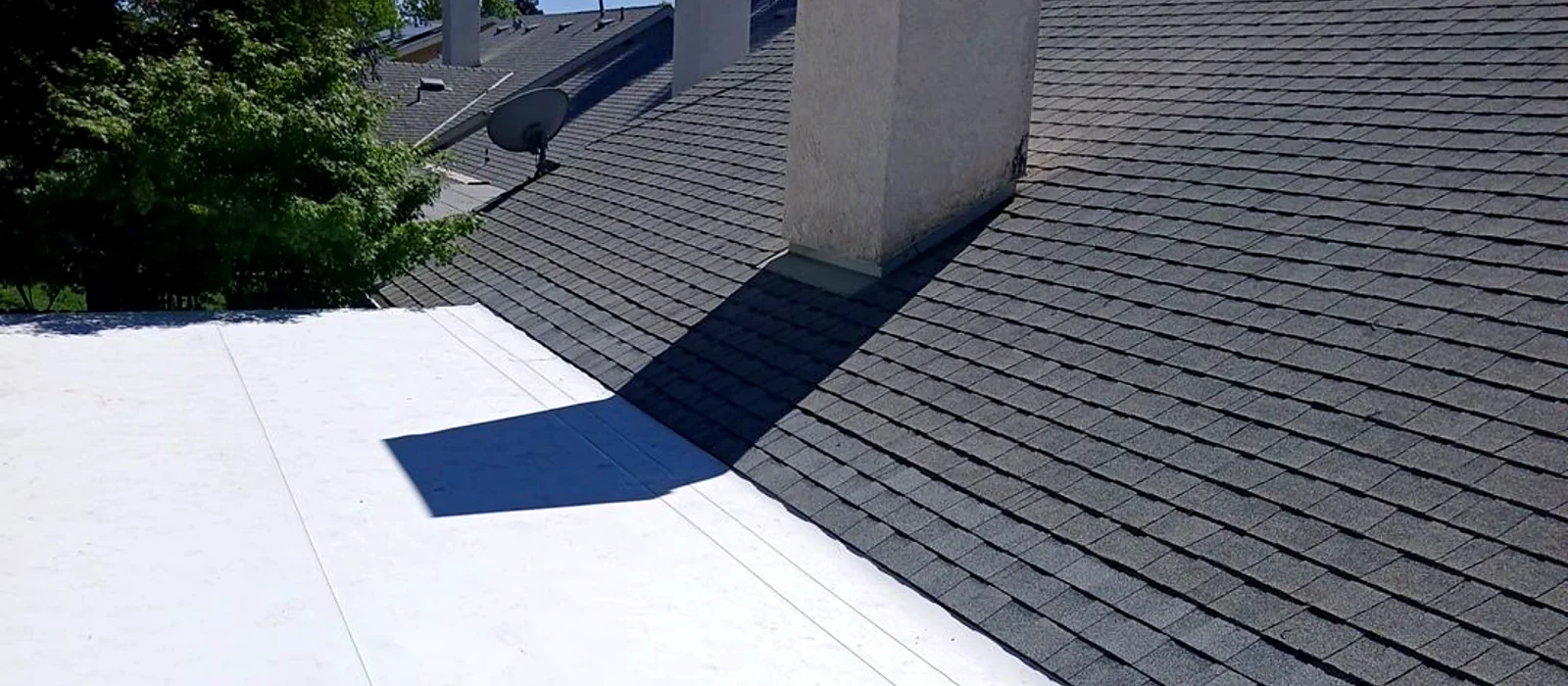 Repaired transition between a white flat patio roof and a composition shingle roof plane in Fresno