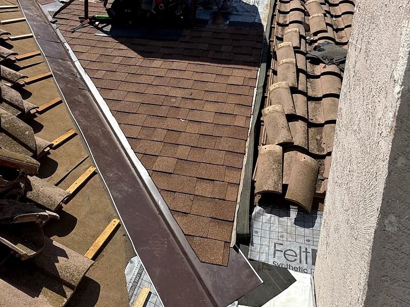 Concrete tile lifted off the battens on a Madera roof with synthetic underlayment and new metal valley flashing going in