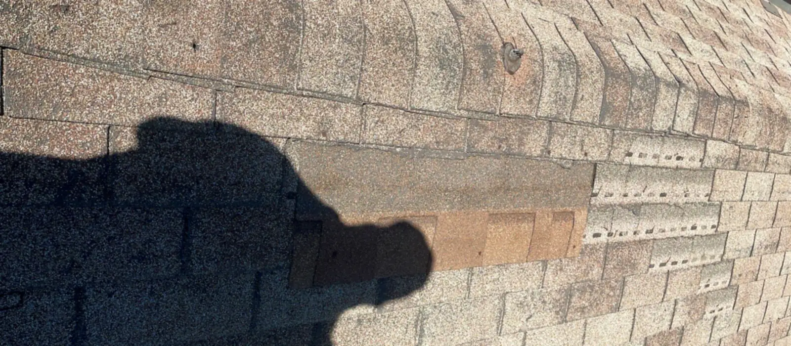 A patch of mismatched shingles on a composition roof where a previous repair was made with the wrong color