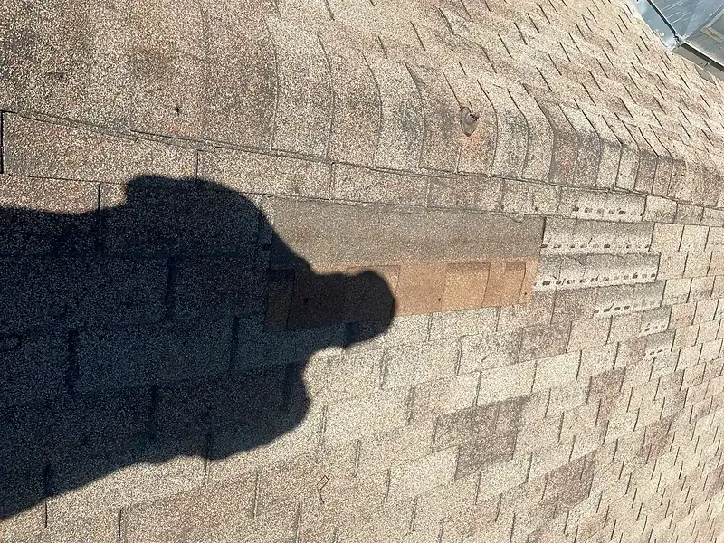 A patch of mismatched shingles on a composition roof where a previous repair was made with the wrong color