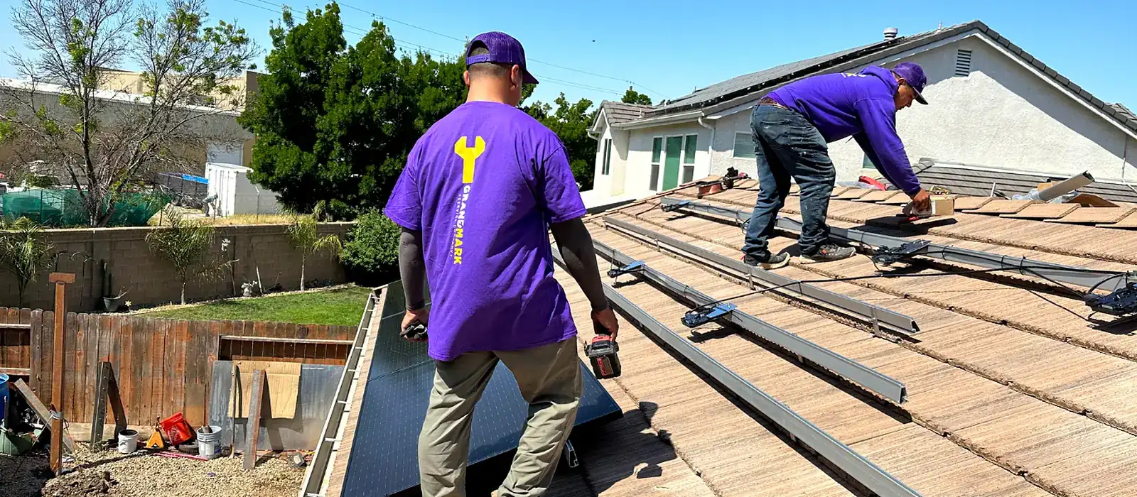 Two Grandmark roofers removing solar panels and mounting rails from a concrete tile roof