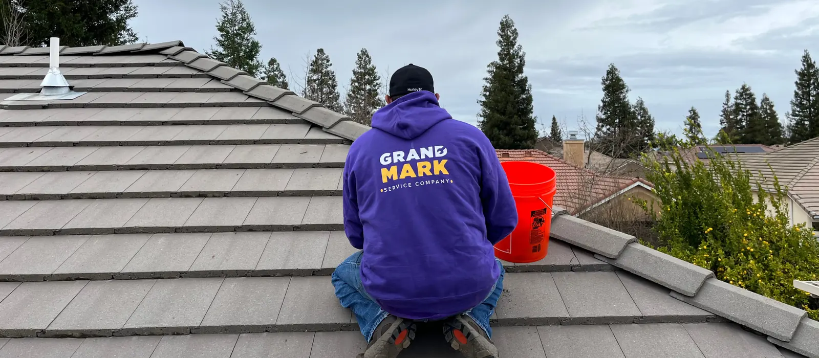 A Grandmark roofer working on the ridge of a concrete tile roof on a Central Valley tract home