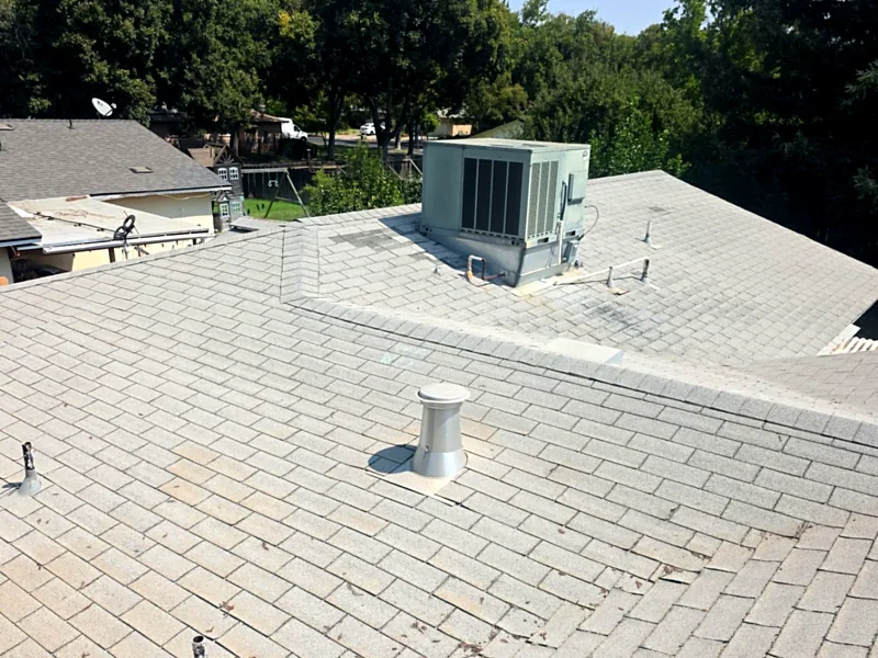 An aging composition shingle roof in Merced with a rooftop package unit, vent pipes and a low-slope section