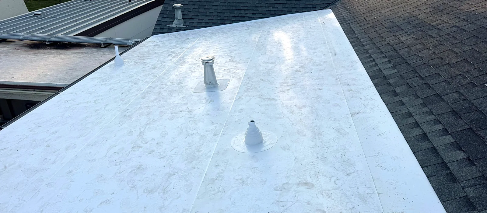 A finished white membrane roof on the low-slope section of a Merced building, with new pipe boots flashed into the sheet