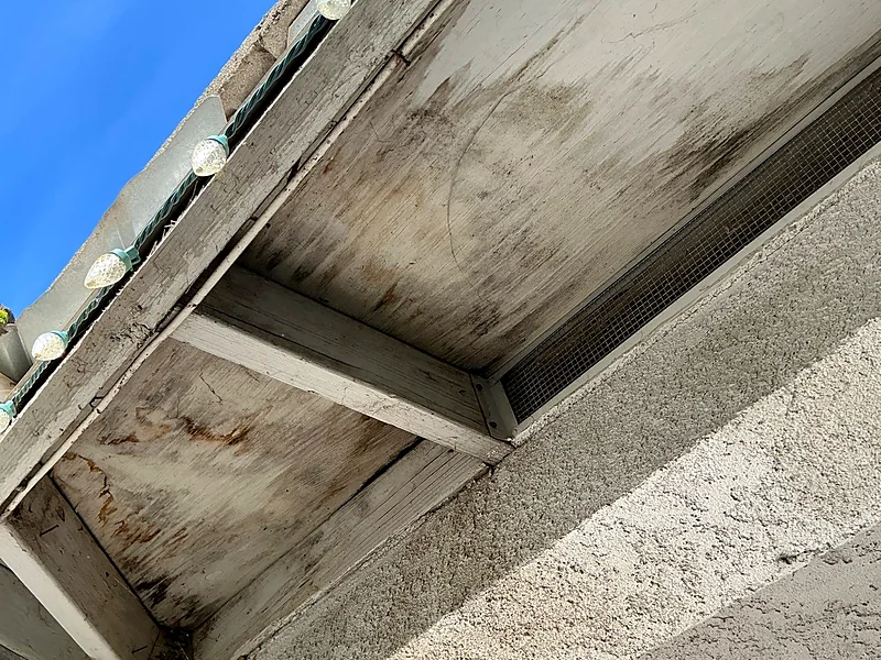 Water-stained and rotting eave boards beneath a failed valley on a Selma tile roof, alongside the attic vent