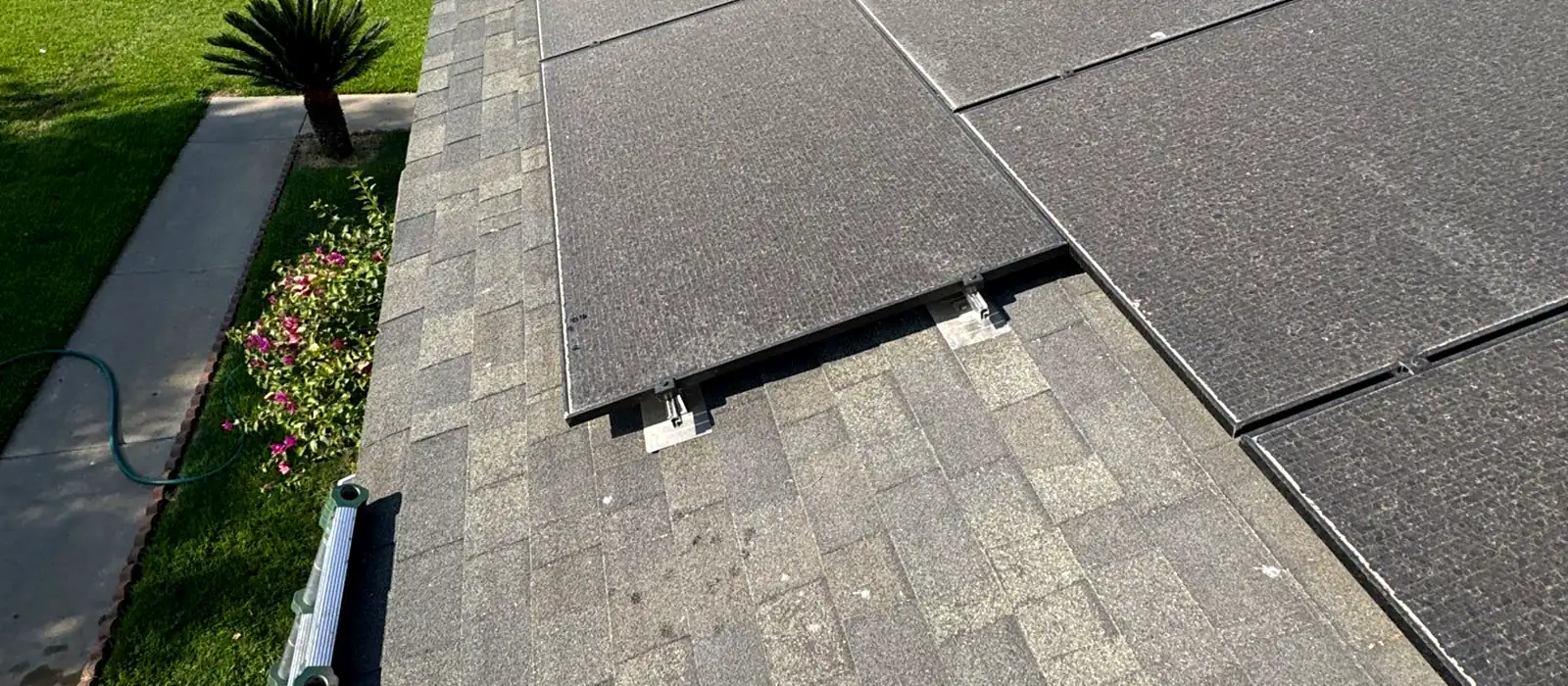 Solar panels mounted on an aging composition shingle roof in Sanger, with the panel rail brackets sitting directly on worn shingles